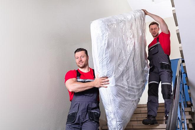 two workers lifting a box spring out of a bedroom in Coconut Creek